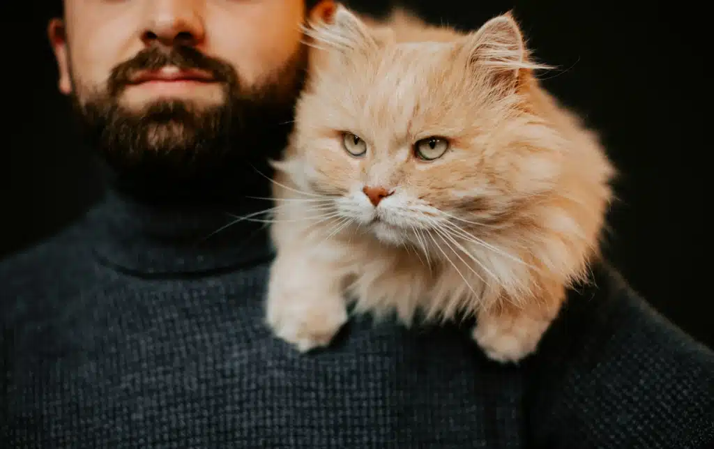 a man holding a cat on his shoulder